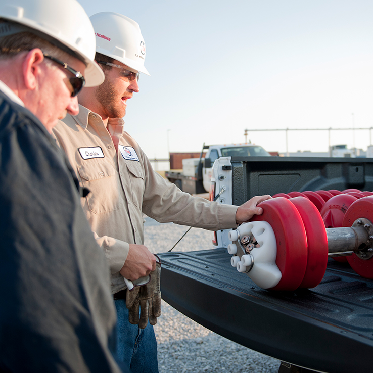 Pigging technicians examining a pipeline pig in a truck bed before launch