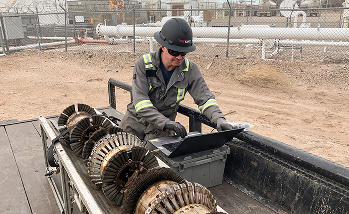 TDW technician working on laptop next to ILI tool in the field