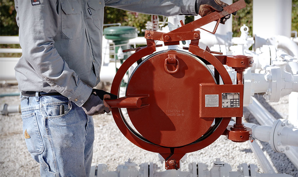 Pipeline technician operates a pigging closure from outside the line of fire.