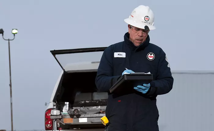 TDW pigging project manager writing on a clipboard at a jobsite