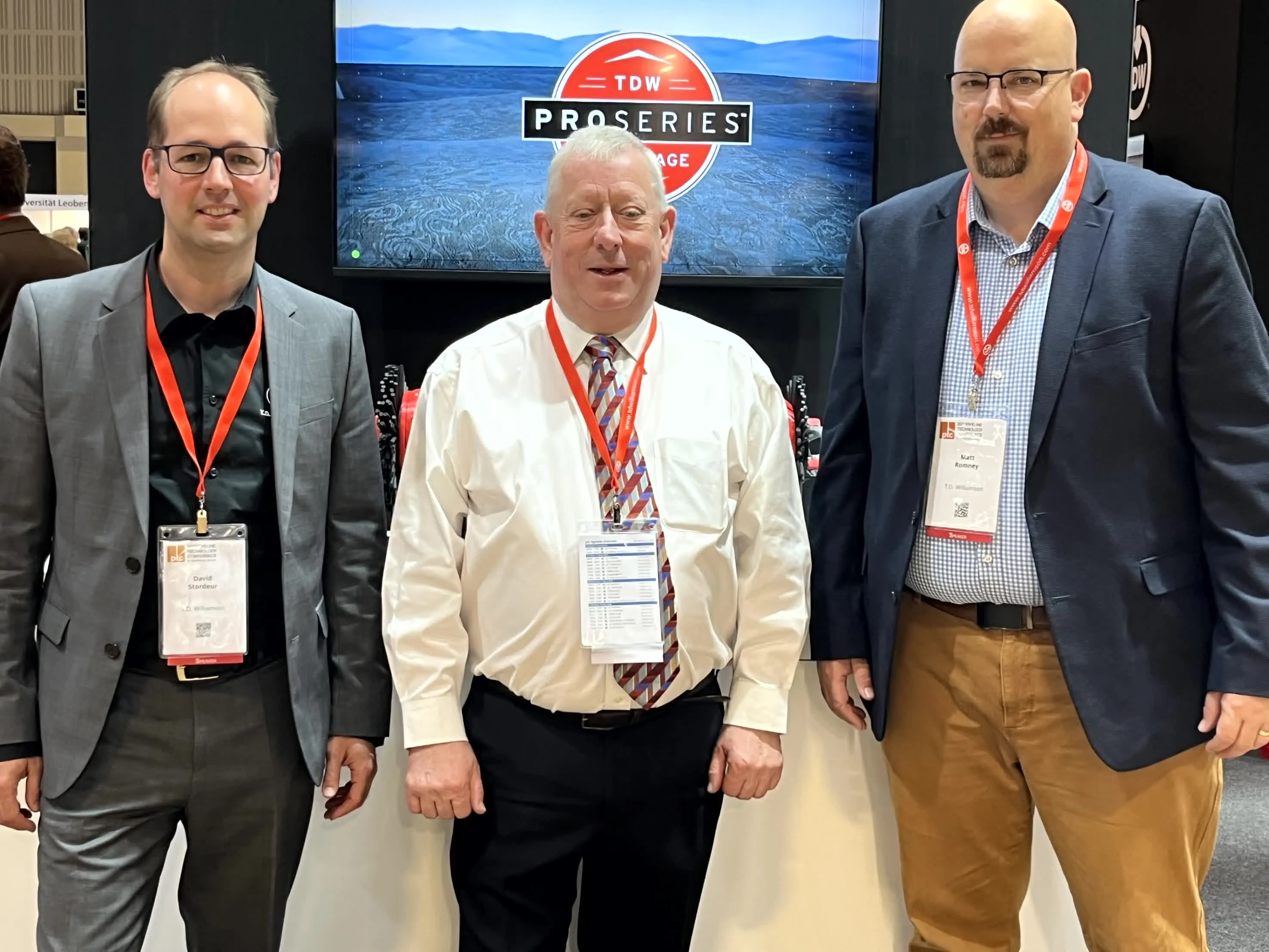 Two TDW employees pictured at an industry trade show with exhibit booths behind them